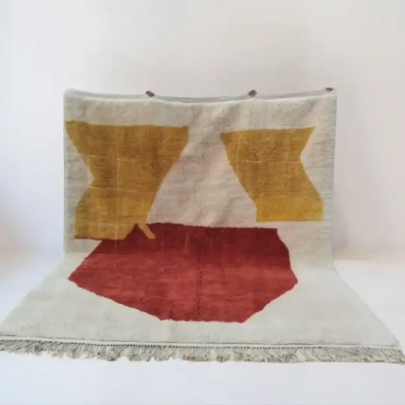A handmade Moroccan Beni Mrirt rug featuring an abstract design with bold golden yellow and warm red shapes on a soft neutral background.