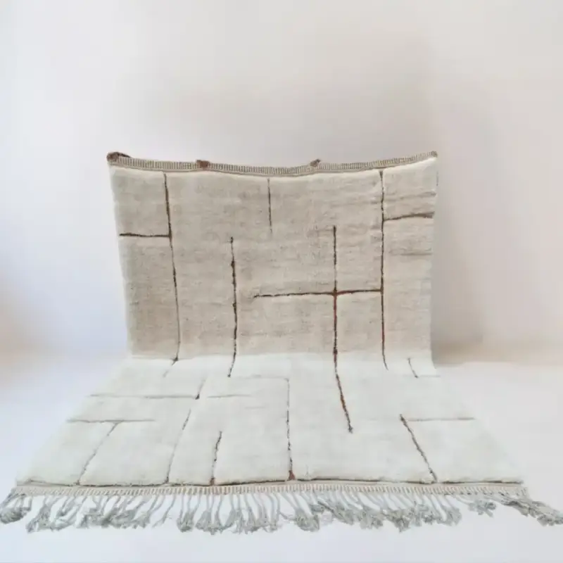 Handwoven Moroccan Beni Mrirt rug featuring a minimalist geometric design with intersecting brown lines on an ivory wool background, crafted from premium lambswool.