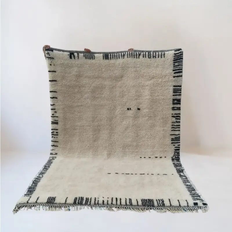 A handmade Beni Mrirt rug in soft ivory with minimal black artistic details, crafted from premium wool for a serene and elegant look.